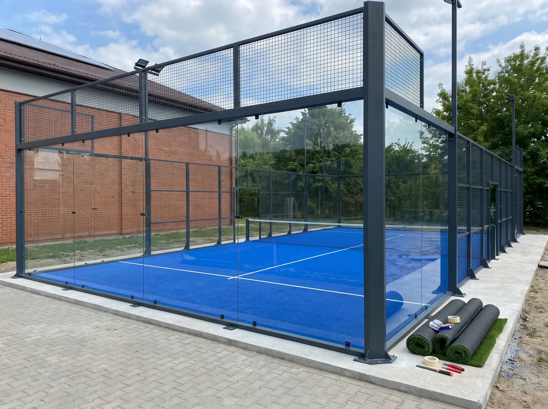 Kort do padla z niebieską nawierzchnią, metalową konstrukcją i szklowaniem